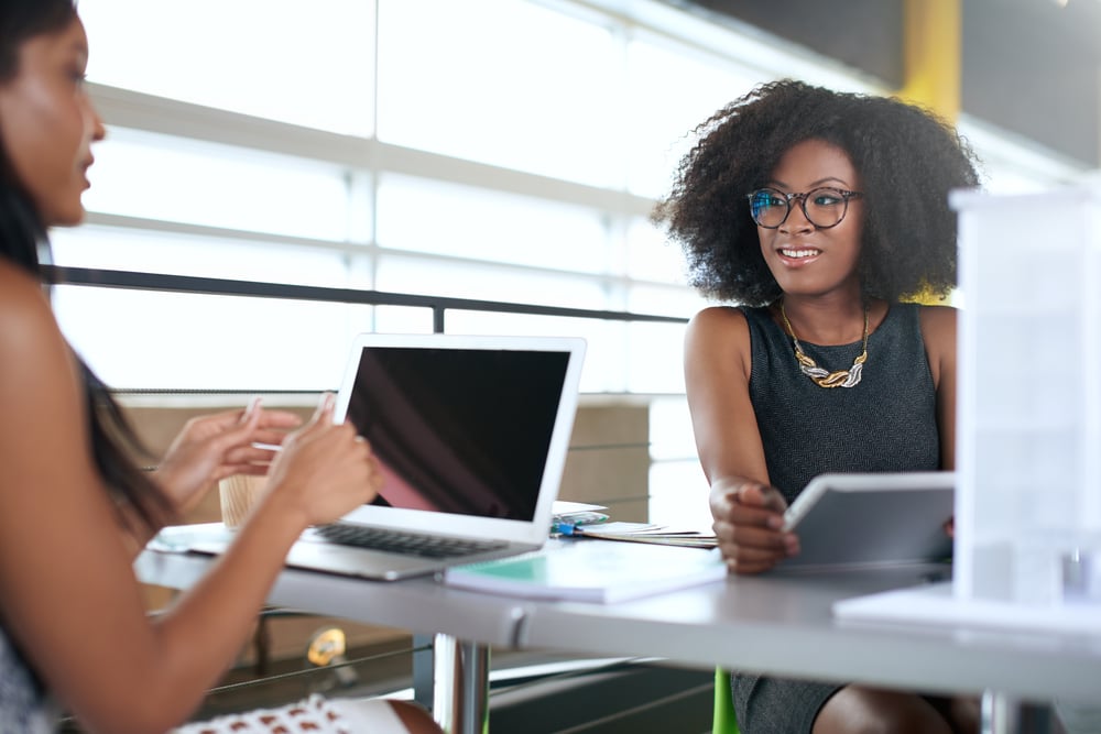 Two women talking in front of a laptop