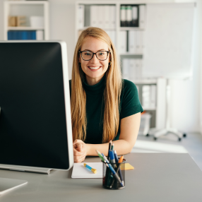 Woman sitting in front of a desktop smiling 